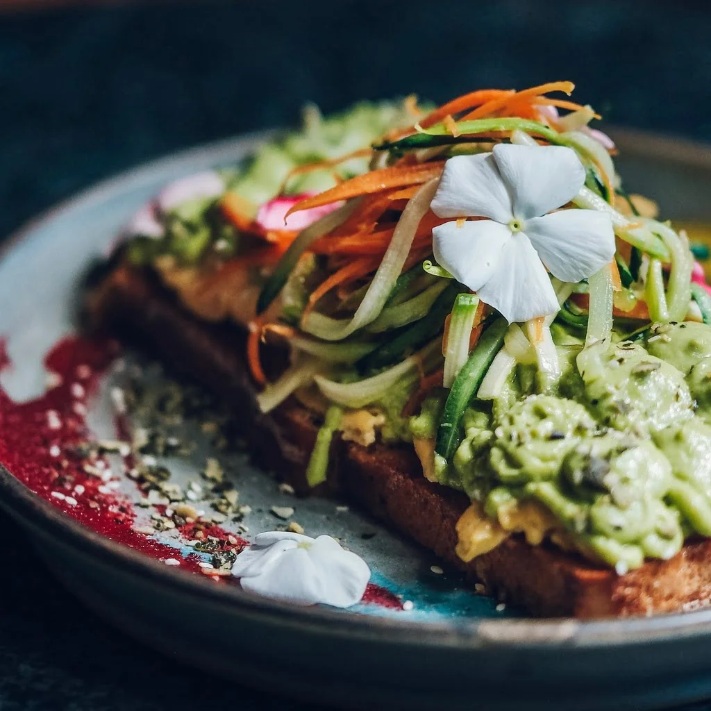 Avocado tost na tanjiru, serviran na brio&scaron; hlebu sa kajganom, avokado kremom i miks salatom.